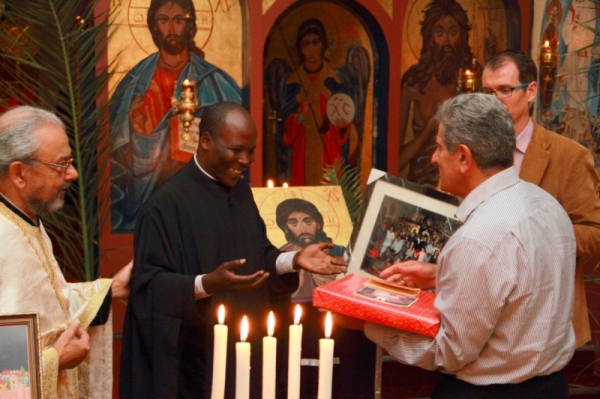 Azar Jammine, a former chairman of the parish council, presents a gift to Fr Athanasius, while Fr George Coconos and Stephen Reynders look on (Photo by Jethro Hayes)